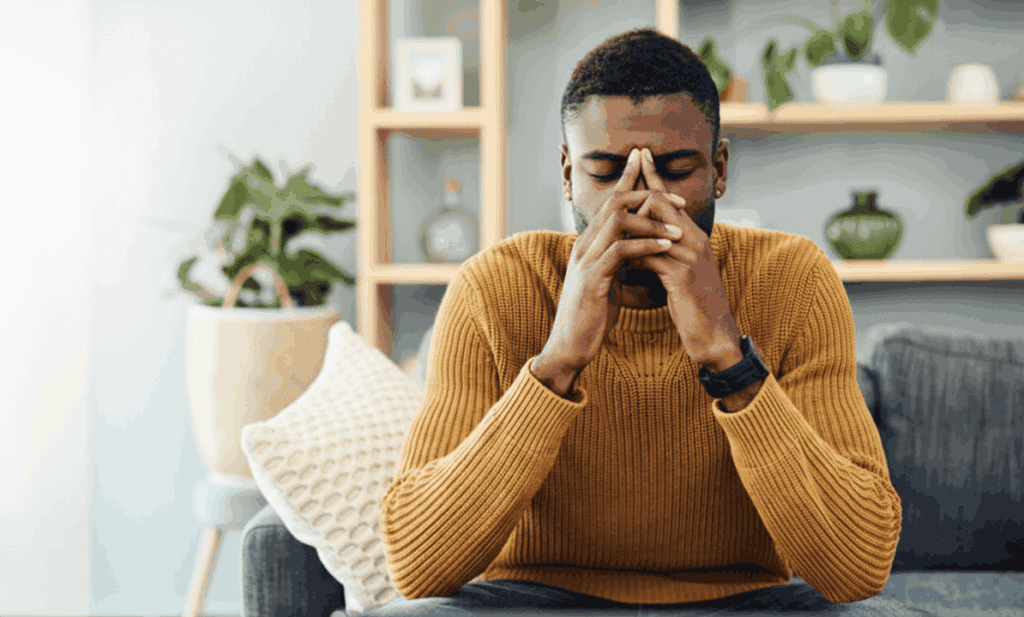 does sativa make you paranoid. Man sitting on the couch with anxiety.